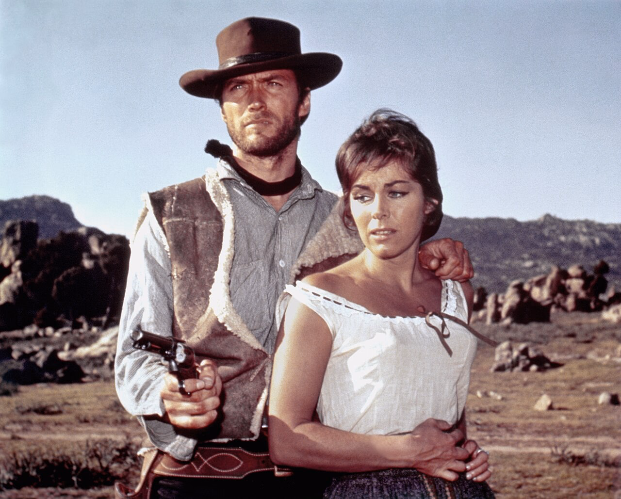 Clint Eastwood mit Hut und Revolver neben Marianne Koch